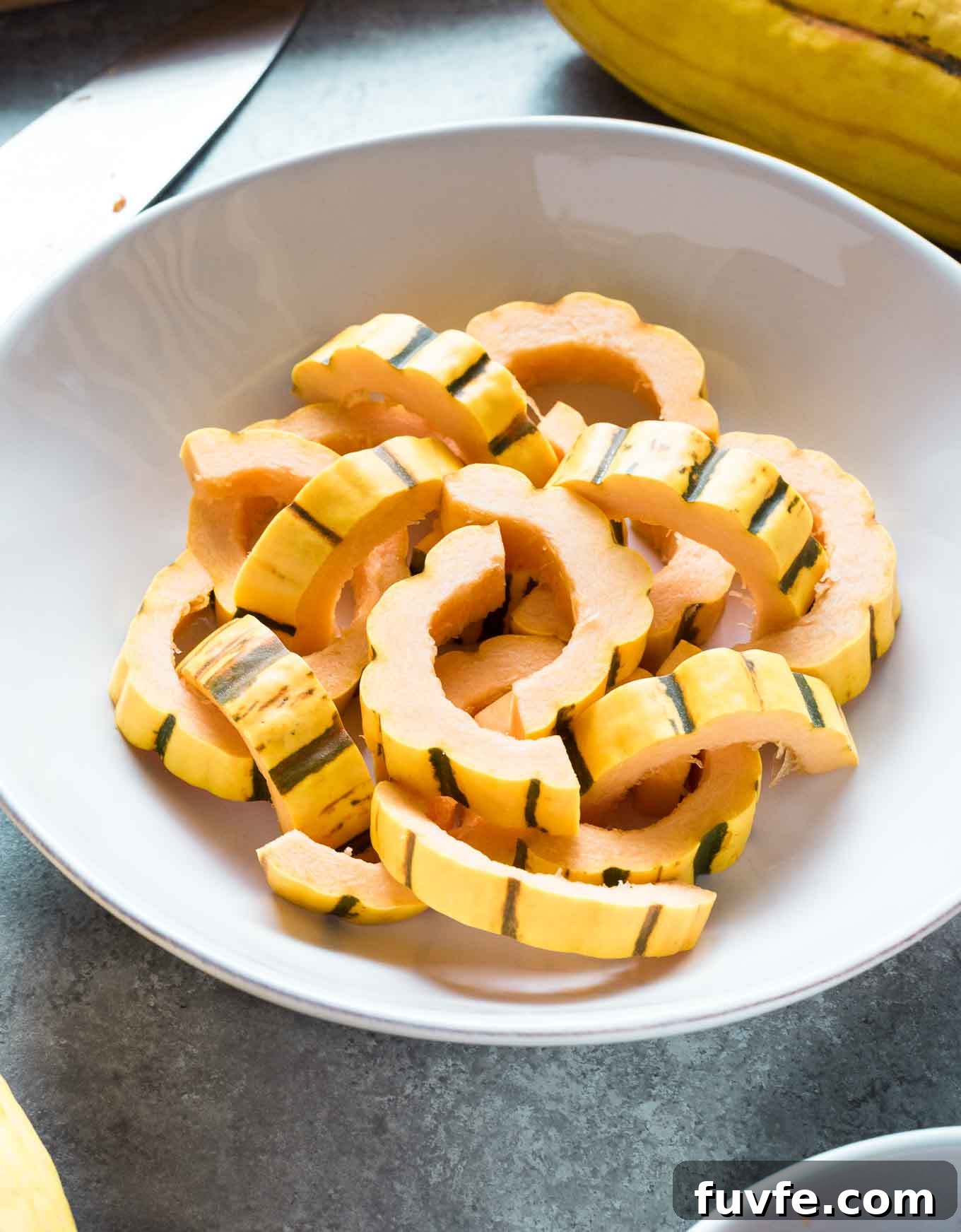 Prepped and sliced delicata squash in a white bowl