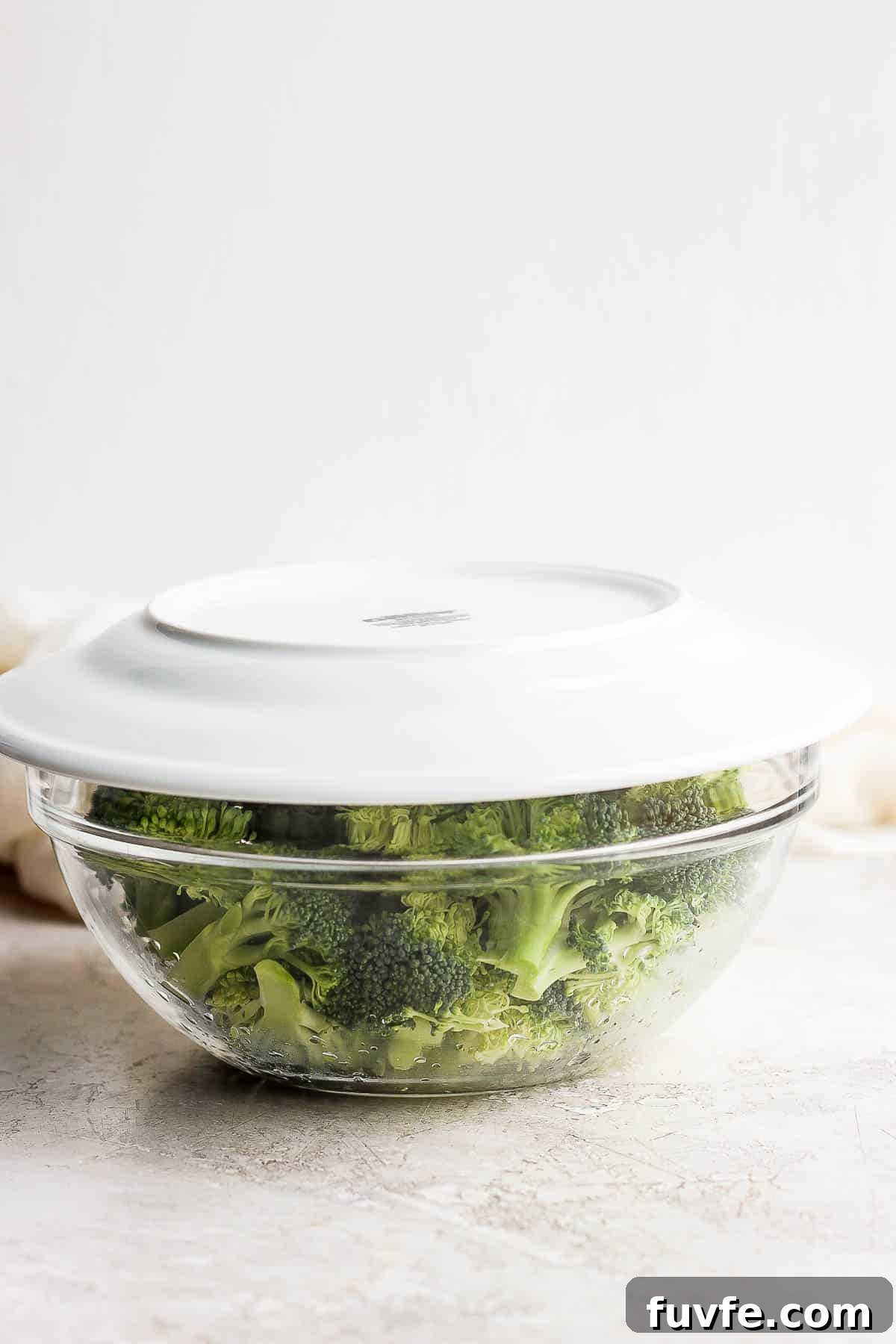 How to Steam Broccoli: Stovetop and Microwave Methods 9 A plate on top of broccoli in a bowl.