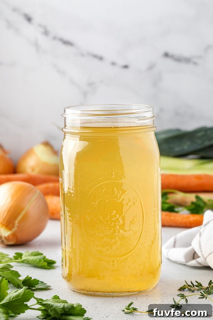 Vegetable broth in a jar surrounded by veggies