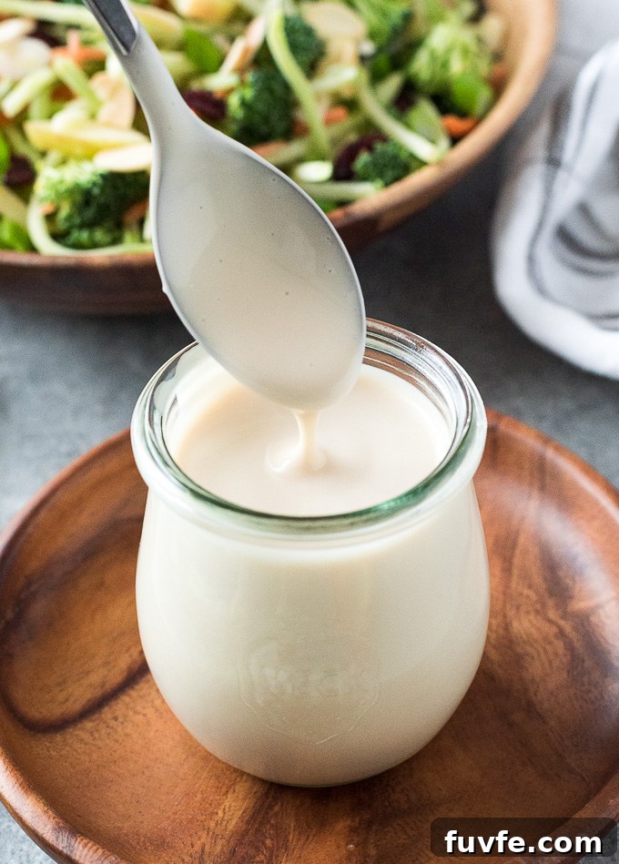 Spoon drizzling coleslaw dressing into a jar