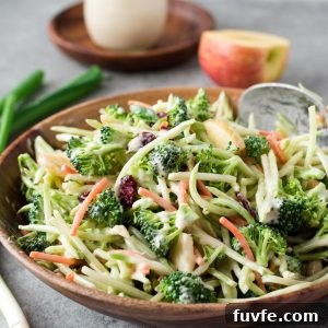 Broccoli slaw in a bowl with jar of dressing behind