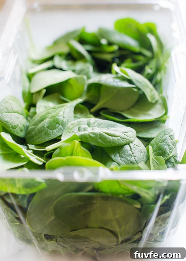 A clear plastic container of baby spinach for a Green Smoothie Bowl