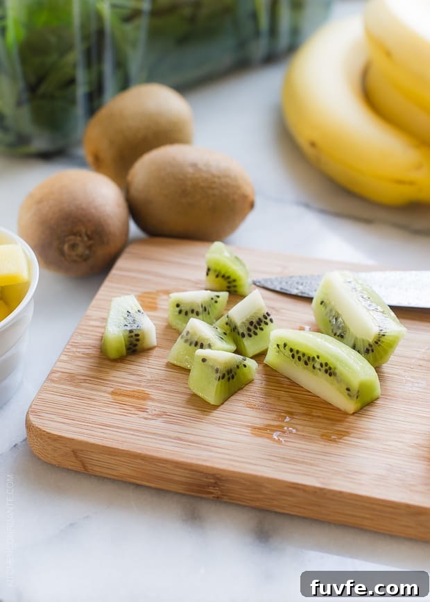 Chopped kiwi on a wooden cutting board for a Green Smoothie Bowl