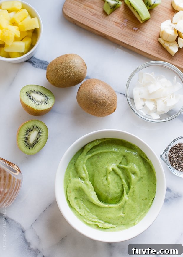 The base of a Green Smoothie Bowl with toppings such as kiwi and coconut on a marble board