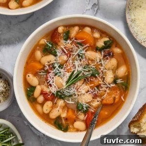 Bowl of vegetarian white bean stew topped with rosemary and parmesan.
