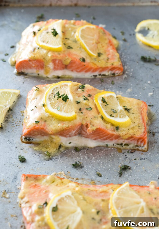 Salmon with lemon dijon sauce on a baking sheet.