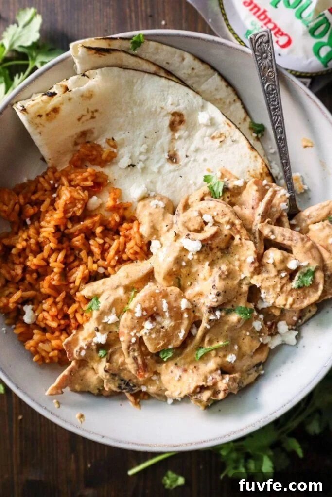 Creamy chipotle shrimp, spanish rice, and flour tortillas in a white ceramic plate. 