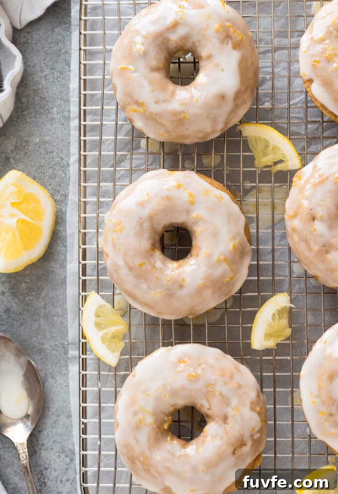 Baked Lemon Donuts Recipe with Zesty Glaze 2 Lemon baked donuts with lemon glaze on a wire rack.