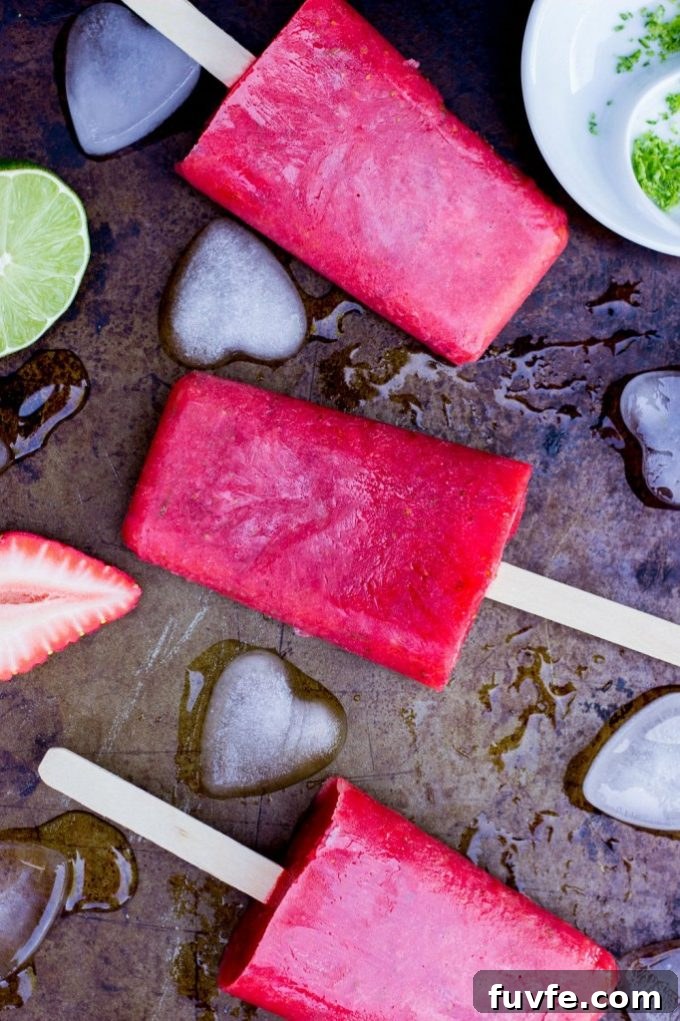 Three strawberry rhubarb popsicles on a dark background.