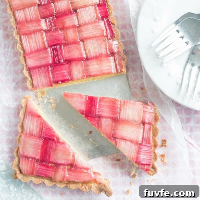 Sliced rhubarb tart next to a white plate with forks on it.