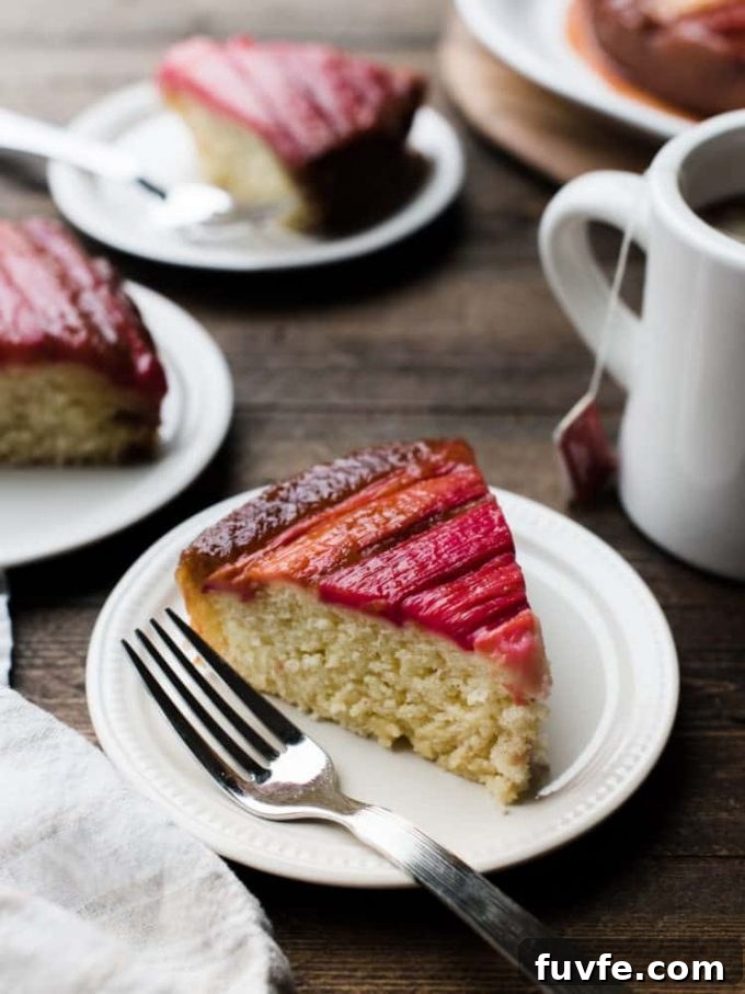 Rhubarb upside down cake on a white plate with a fork.