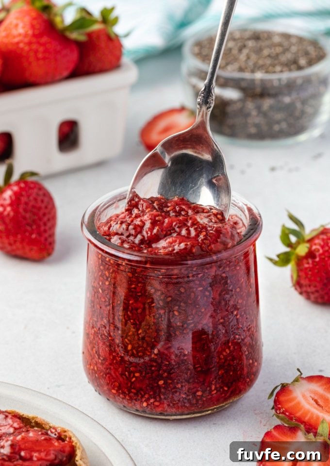 No-Cook Chia Seed Jam Recipe 2 Spoon digging into jar of strawberry chia jam