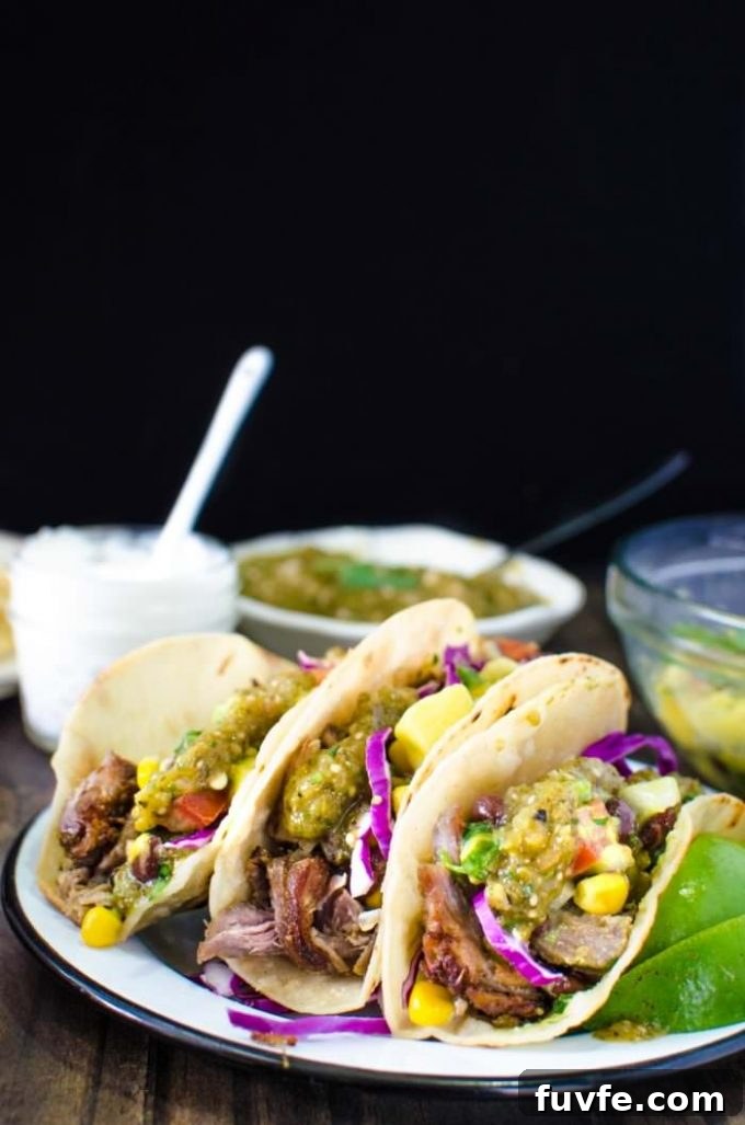 Three pork carnitas tacos on a white plate.