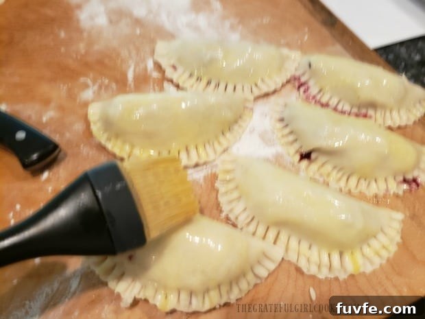 A beaten egg is brushed over the handpies before cooking.