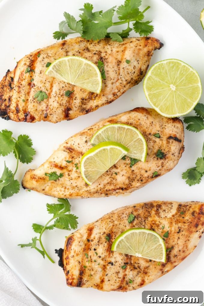 Grilled tequila lime chicken on a platter with lime slices and cilantro