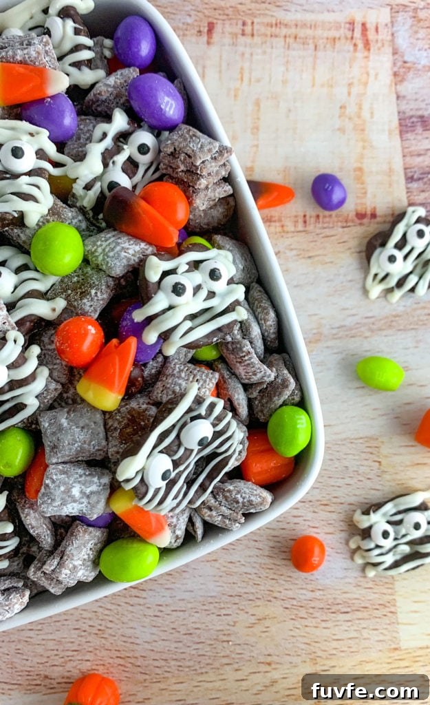 Spooky Halloween Chex Mix Recipe for Parties and Treats 8 A bowl of chocolate covered chex, topped with decorated pretzels and colored M&Ms.