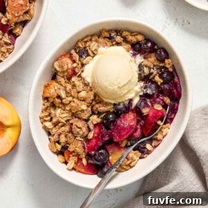 Peach blueberry crisp in a bowl with ice cream.