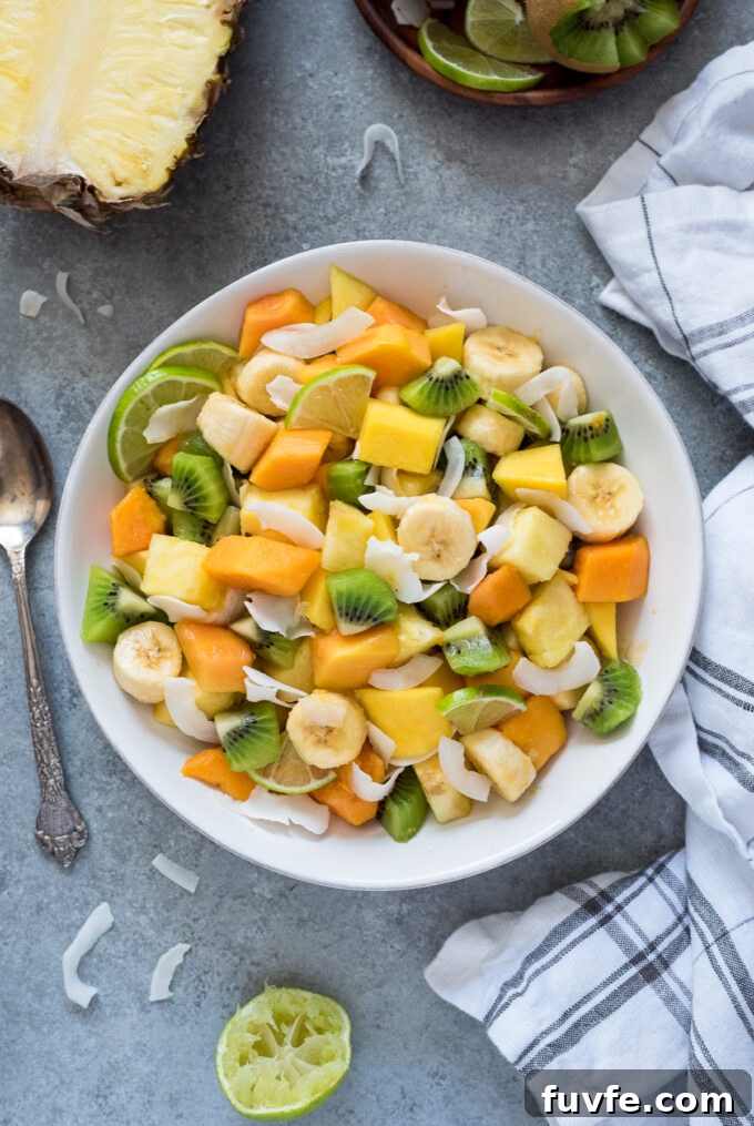 Refreshing Tropical Fruit Salad with Coconut and Lime 5 Fruit salad with tropical fruit in a white bowl.