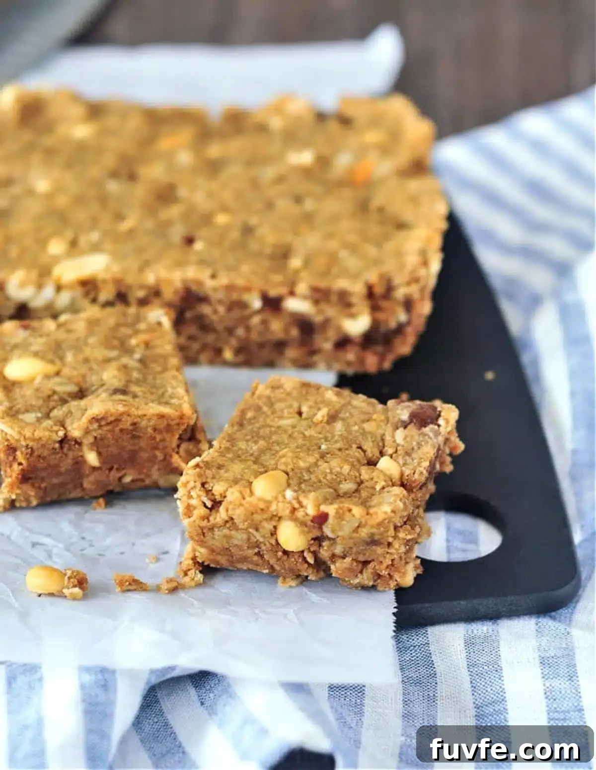 Vegan peanut butter bars on a cutting board, two cut into squares and larger slab ready to slice.