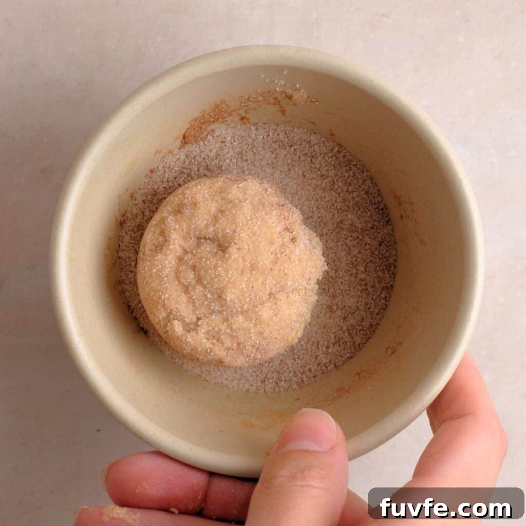 Cookie dough balls being coated in cinnamon & sugar mixture.