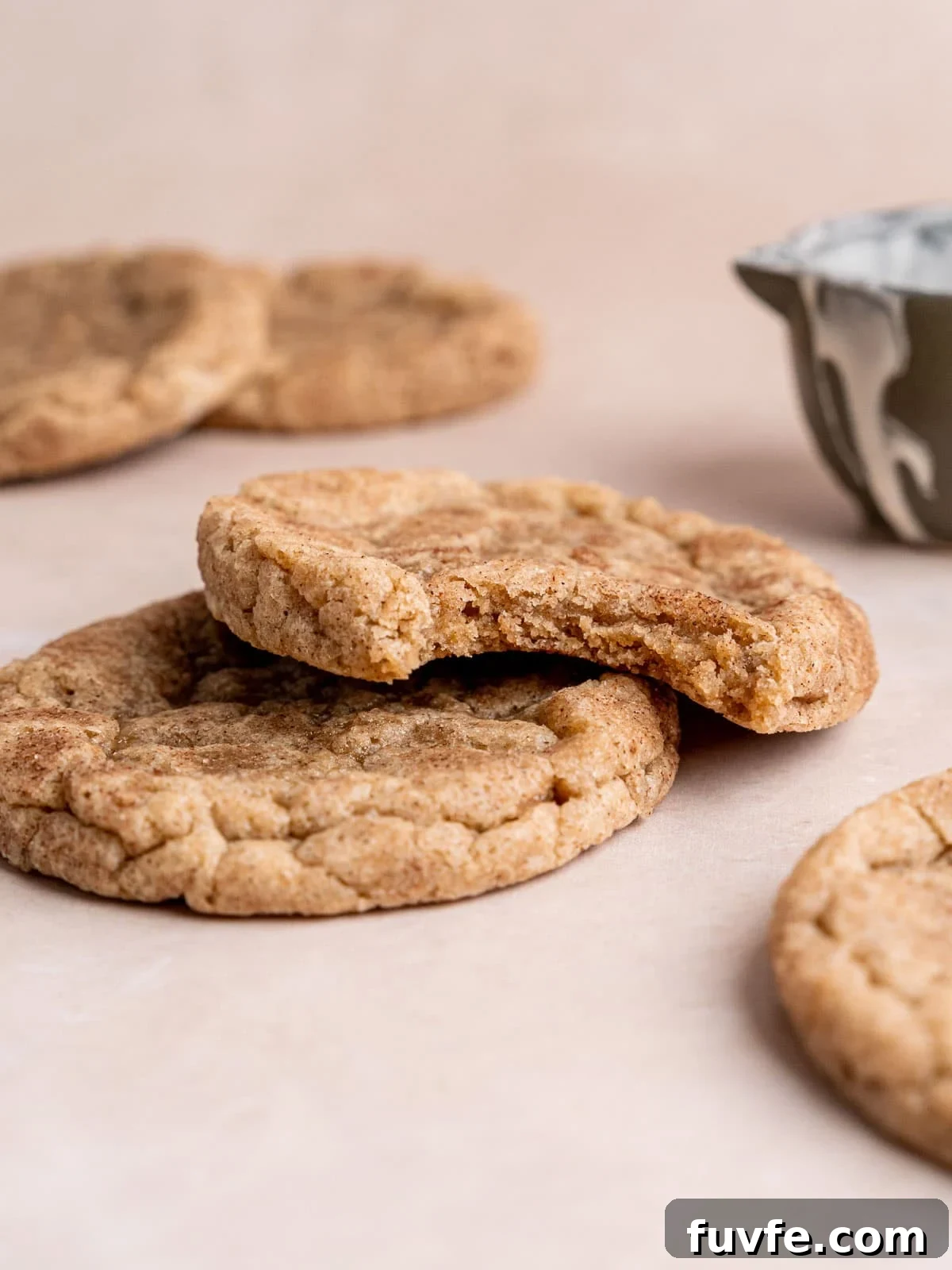 Stacked snickerdoodle cookies with a bite taken out of the top cookie.