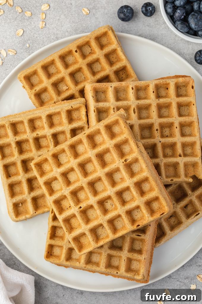 Oat flour waffles piled on a white plate