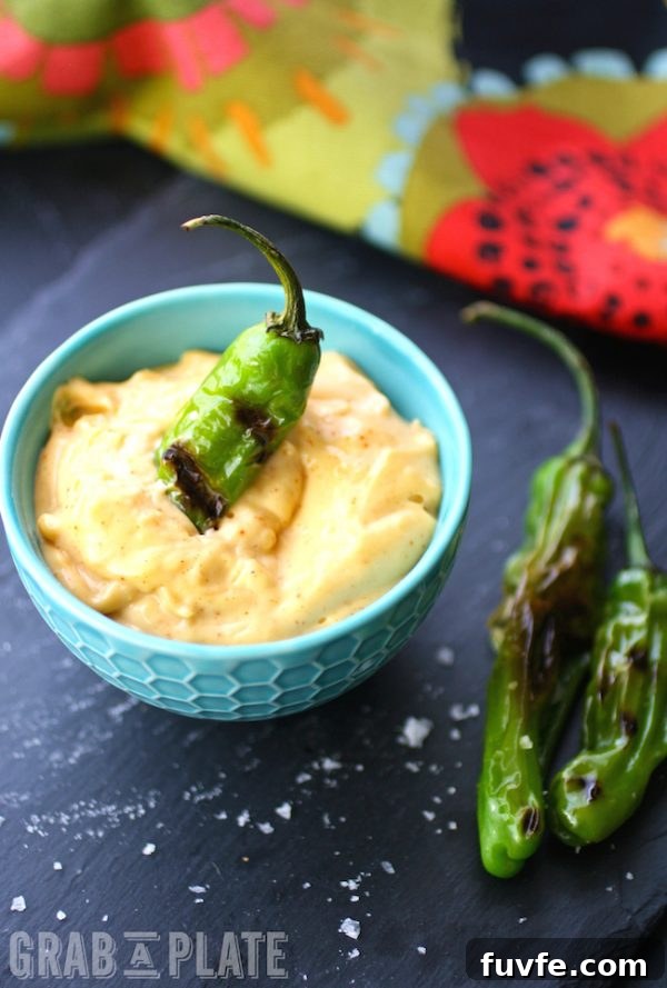Blistered shishito pepper resting in a bowl of aioli