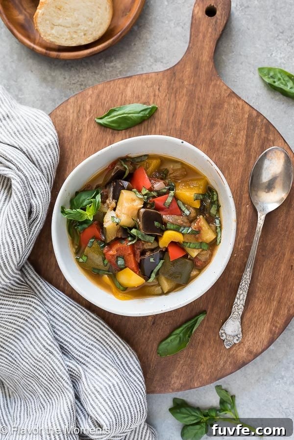 overhead shot of bowl of ratatouille on cutting board with spoon