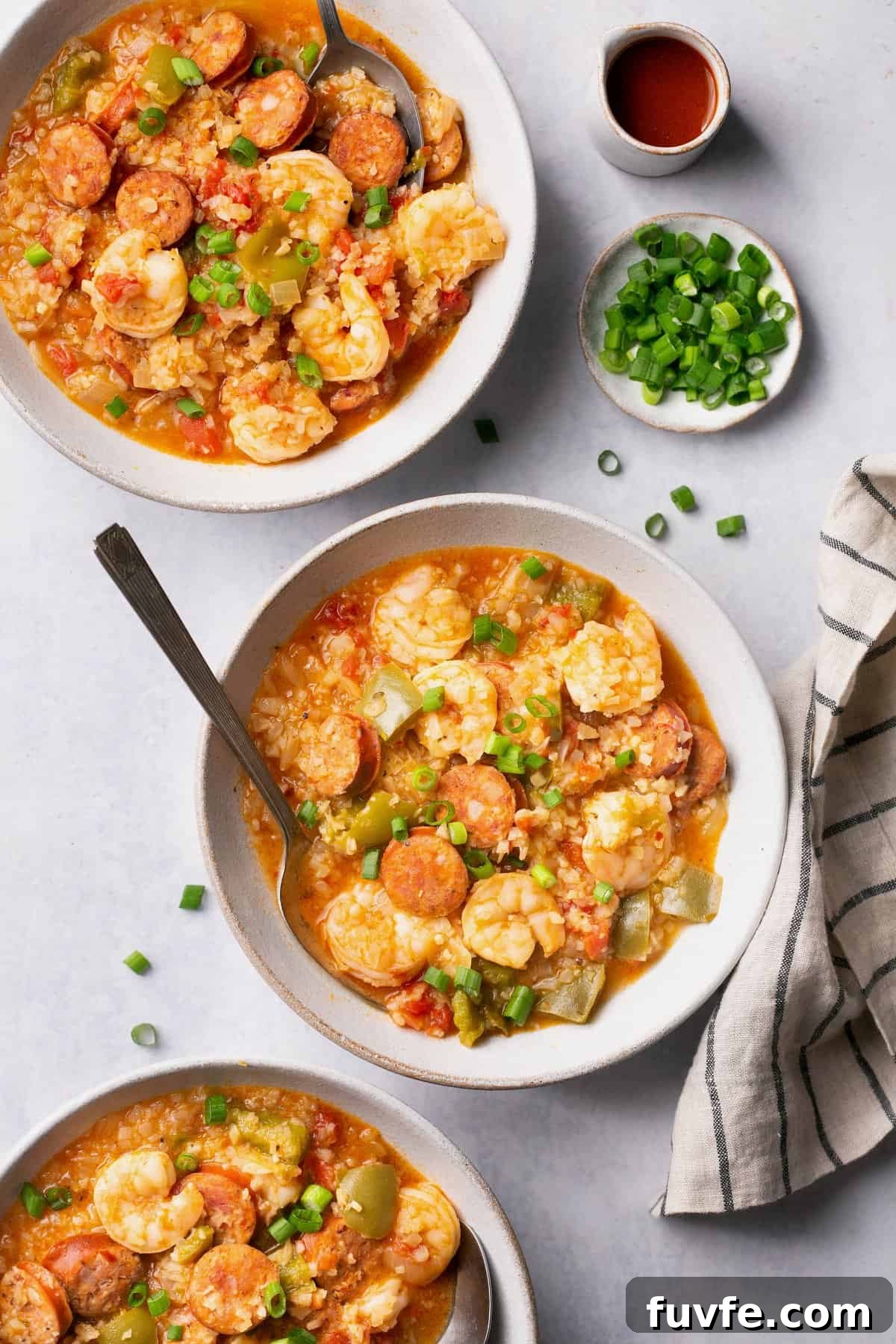 and overhead shot of two bowls of jambalaya soup topped with green onions