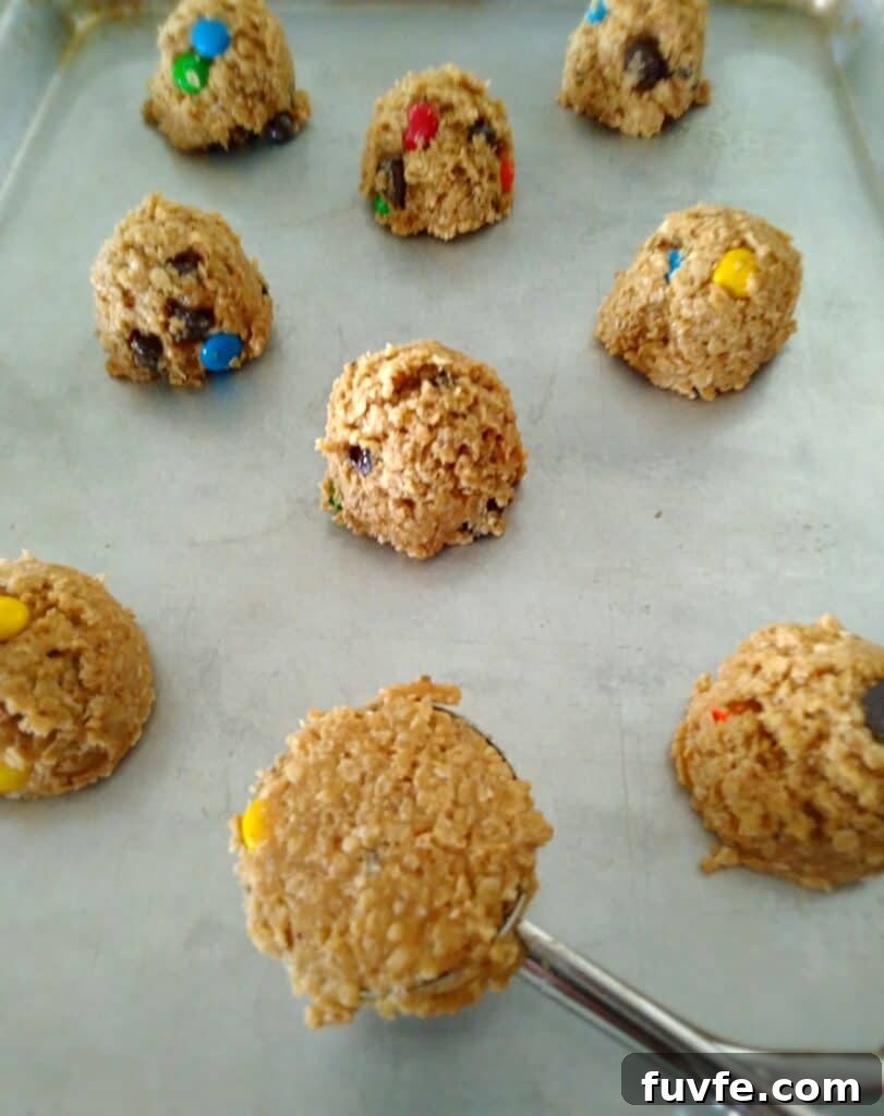 scooping Monster cookie dough onto a baking tray.