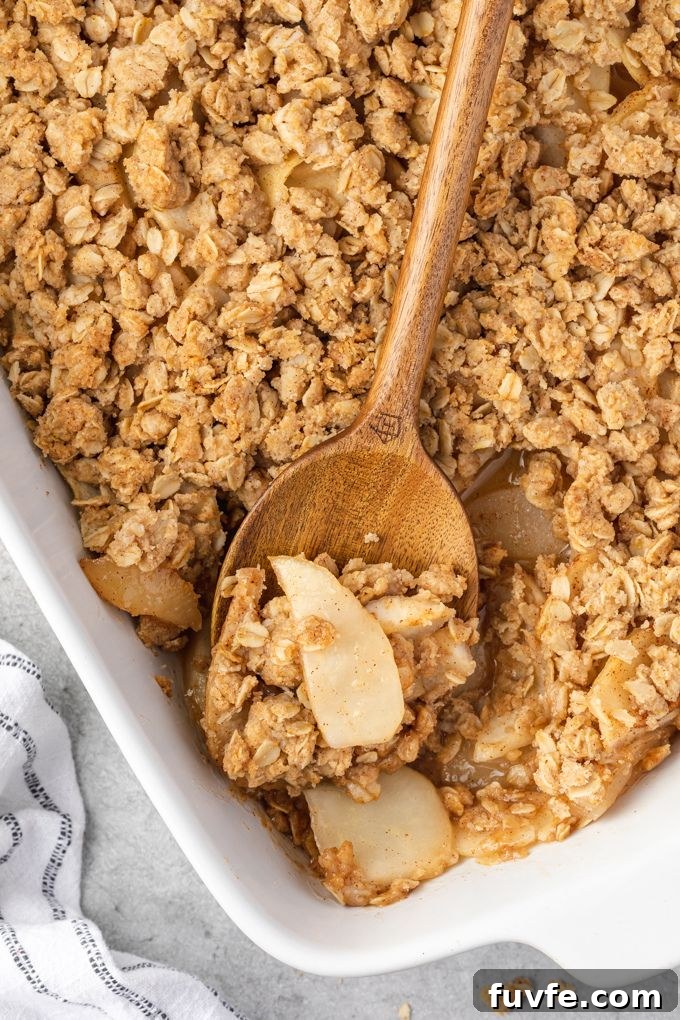 Wooden spoon with pear crisp in baking dish