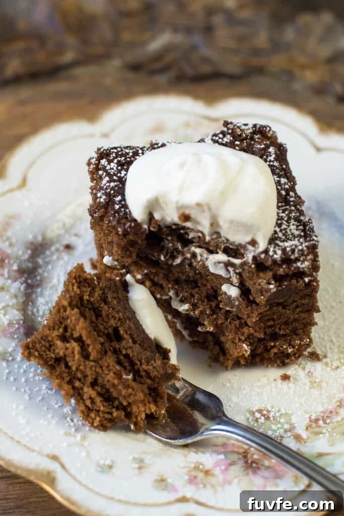 Warm Gingerbread Cake Recipe with Spiced Molasses Glaze 9 A fork resting on a plate after pulling away a bite of gingerbread cake.