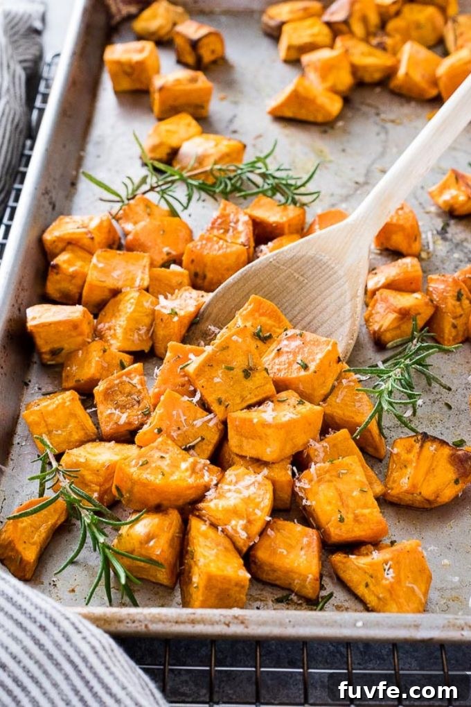 Oven Roasted Sweet Potatoes Recipe with Garlic and Herbs 6 Wooden spoonful of roasted sweet potatoes on baking sheet