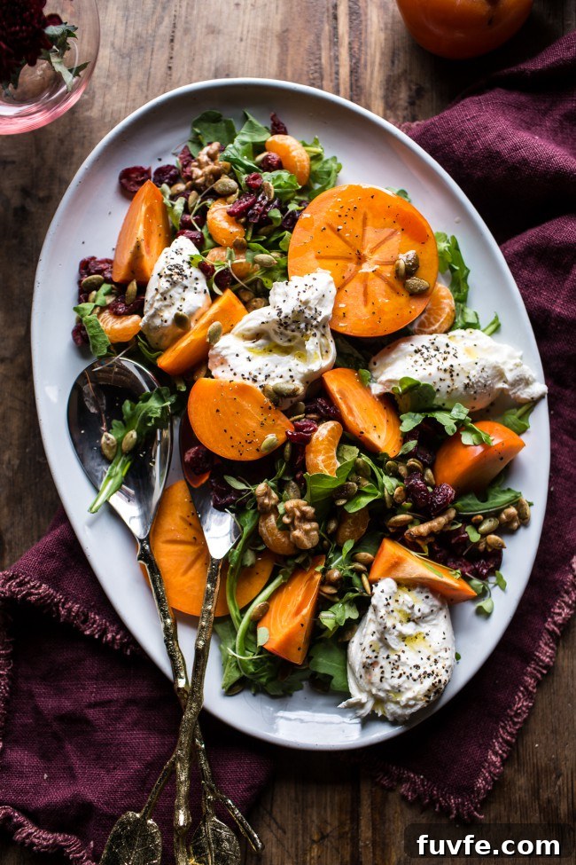 Overhead view of a cranberry persimmon salad on a white platter.