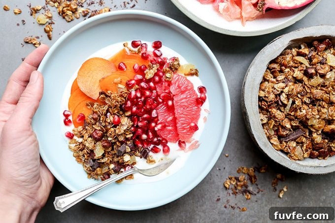 a winter fruit and yogurt bowl, with a hand wrapped around the edge.