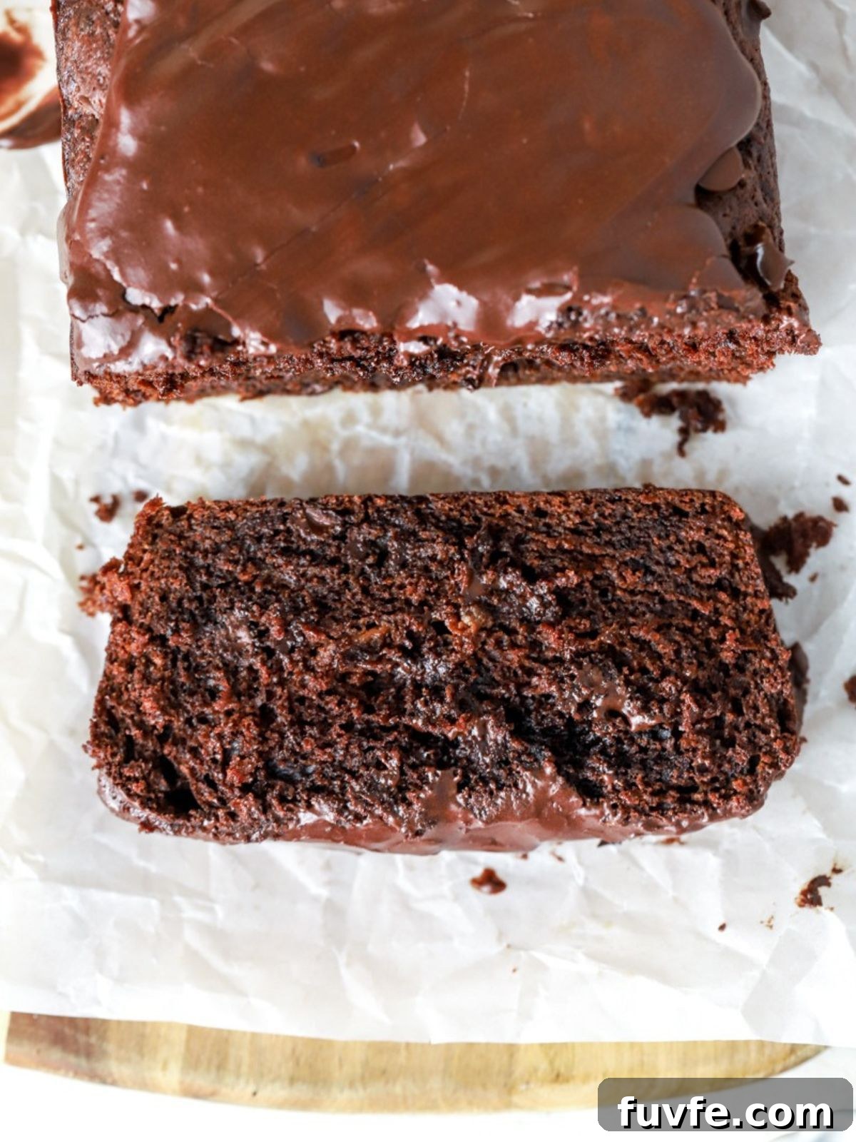 A slice of glazed chocolate loaf cake next to the loaf.