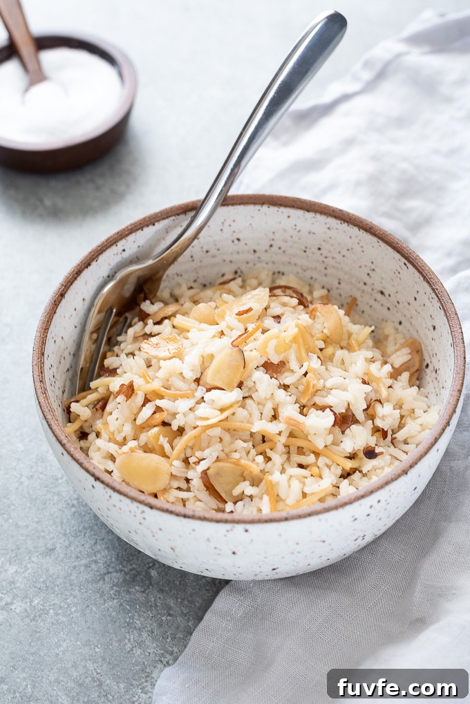 Fragrant Almond Rice Pilaf Recipe with Toasted Almonds 6 Fork nestled into a bowl of rice pilaf