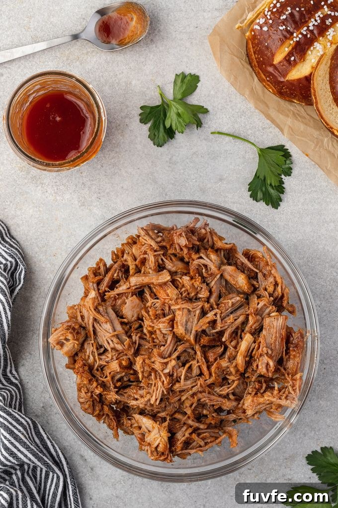 Tender Smoky Instant Pot Pulled Pork with Tangy BBQ Sauce 6 Instant pot pulled pork in mixing bowl with bbq sauce