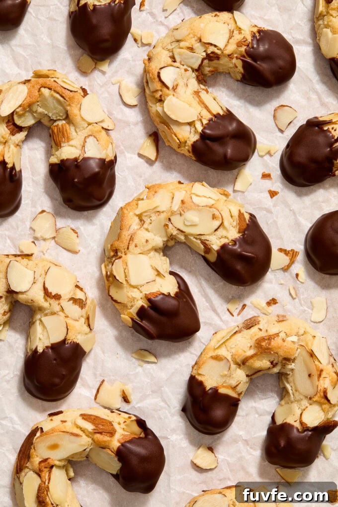 Chocolate-Dipped Almond Horn Cookies 2 Almond horn cookies on parchment paper.