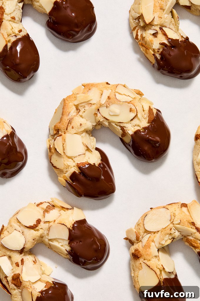 Chocolate-Dipped Almond Horn Cookies 10 Chocolate dipped almond horn cookies on parchment paper.