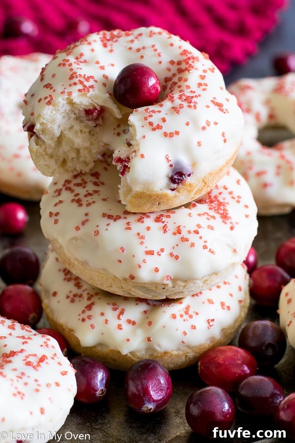 A stack of three glazed cranberry donuts.