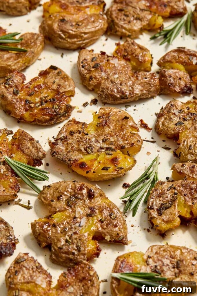 Crispy Smashed Potatoes with Garlic and Herbs 6 Smashed roasted potatoes on a sheet pan with rosemary.