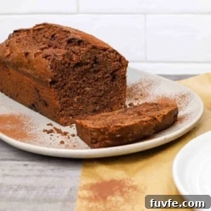 15 Irresistible Chocolate Sourdough Recipes to Try Today 10 double chocolate sourdough banana bread loaf on a plate with one slice cut, dusted with cocoa powder and served on parchment paper.