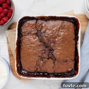 15 Irresistible Chocolate Sourdough Recipes to Try Today 11 Sourdough chocolate cobbler baked in a square white baking dish. This self saucing pudding is displayed with a bowl of fresh raspberries.