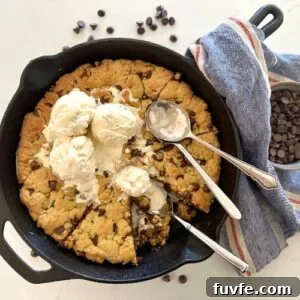 15 Irresistible Chocolate Sourdough Recipes to Try Today 28 Sourdough Cookie Skillet with chocolate chips - Recipe Feature Image. This image is of a cast iron skillet filled with a giant sourdough chocolate chip cookie baked in the oven and then topped with vanilla ice cream. There are three spoons in the skillet and some of the giant cookie has been eaten.