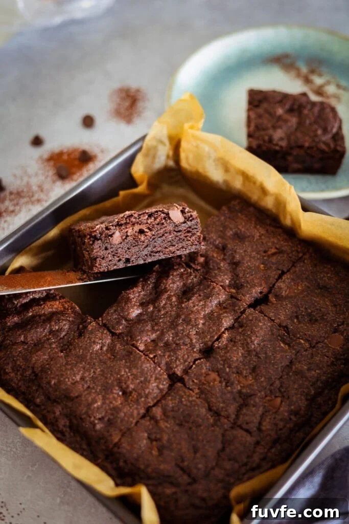 15 Irresistible Chocolate Sourdough Recipes to Try Today 29 Sourdough chocolate brownie that has been baked and sliced into 9 equal pieces. One of the pieces is being lifted out of the pan so you can see the rich and fudgey interior.