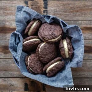 15 Irresistible Chocolate Sourdough Recipes to Try Today 6 SOURDOUGH CHOCOLATE SANDWICH COOKIES sitting in a blue dish towel on a wooden counter top.