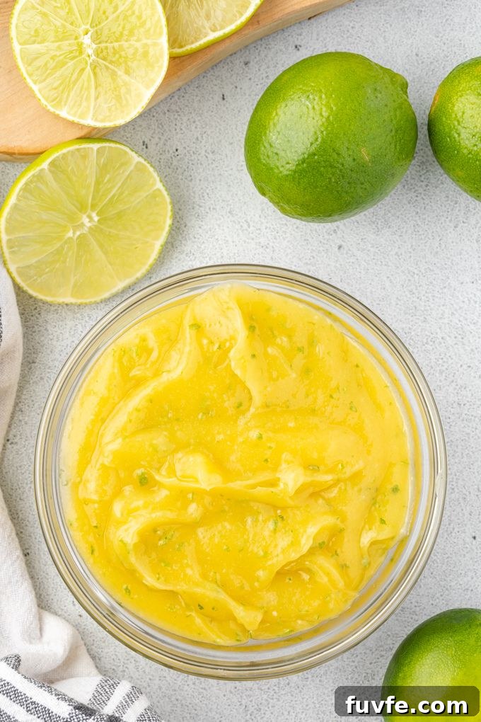 Lime Curd in a glass bowl surrounded by limes