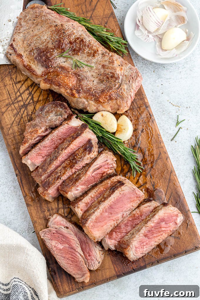 Pan-Seared Steak Recipe with Garlic Butter 7 Butter basted steaks on cutting board with rosemary and garlic