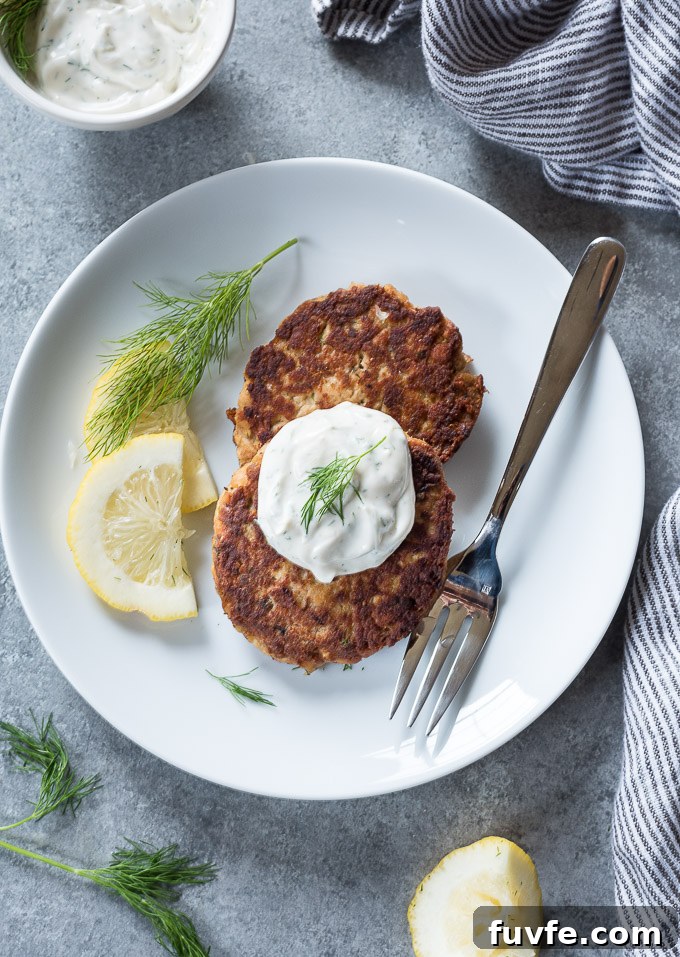 Salmon patties on a plate topped with lemon dill sauce